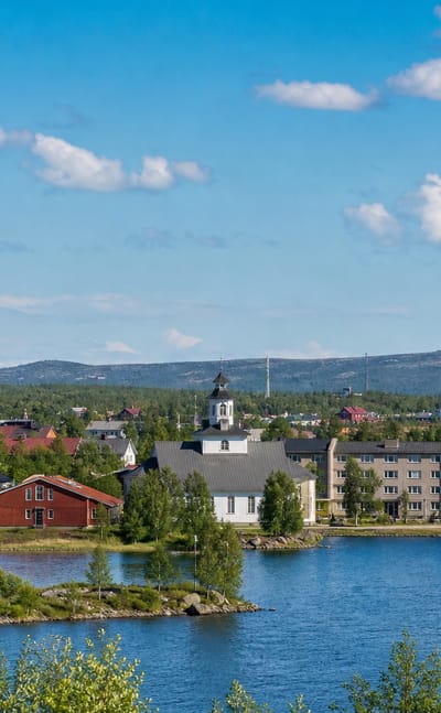 Arjeplog's white church spire rising above lakeside buildings on the shore of Hornavan in Swedish Lapland.
