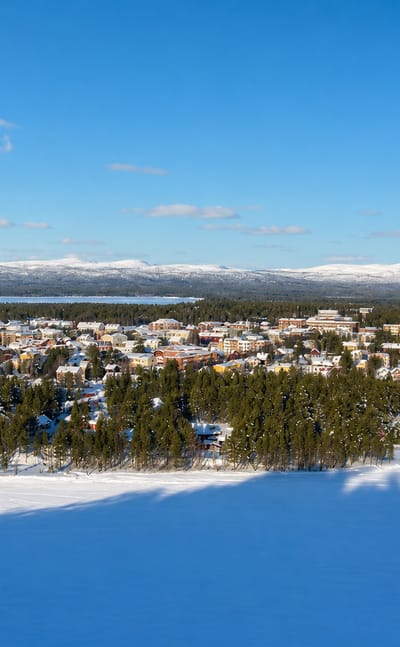 Snow-covered Arvidsjaur nestled in boreal forest with a frozen lake and distant fells in winter
