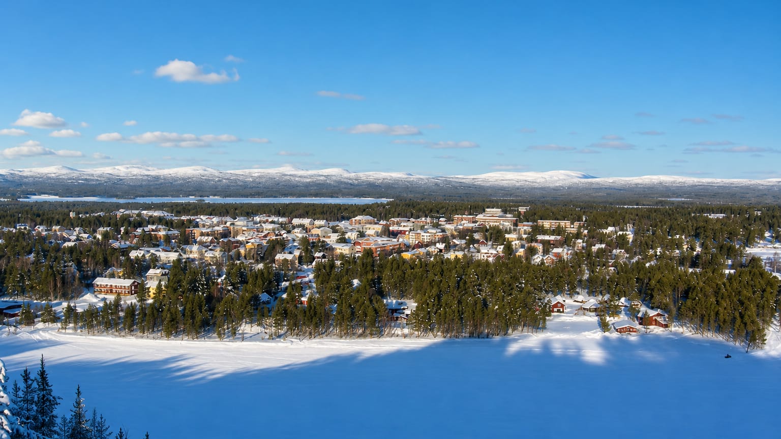 Snow-covered Arvidsjaur nestled in boreal forest with a frozen lake and distant fells in winter