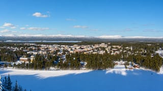 Snow-covered Arvidsjaur nestled in boreal forest with a frozen lake and distant fells in winter