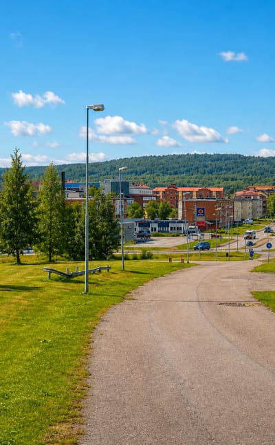 Summer townscape of Gallivare, northern Sweden, with a yellow wooden house, apartment blocks and forested hills.