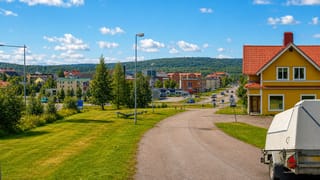 Summer townscape of Gallivare, northern Sweden, with a yellow wooden house, apartment blocks and forested hills.