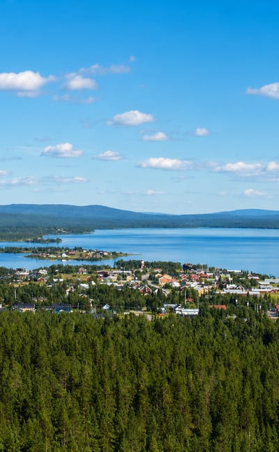 Jukkasjarvi village, Sweden, spread along a lakeshore amid vast Lapland forest with distant fells