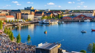 Summer waterfront in Lulea, Sweden, with harbour buildings, boats and a crowd gathered by an event stage