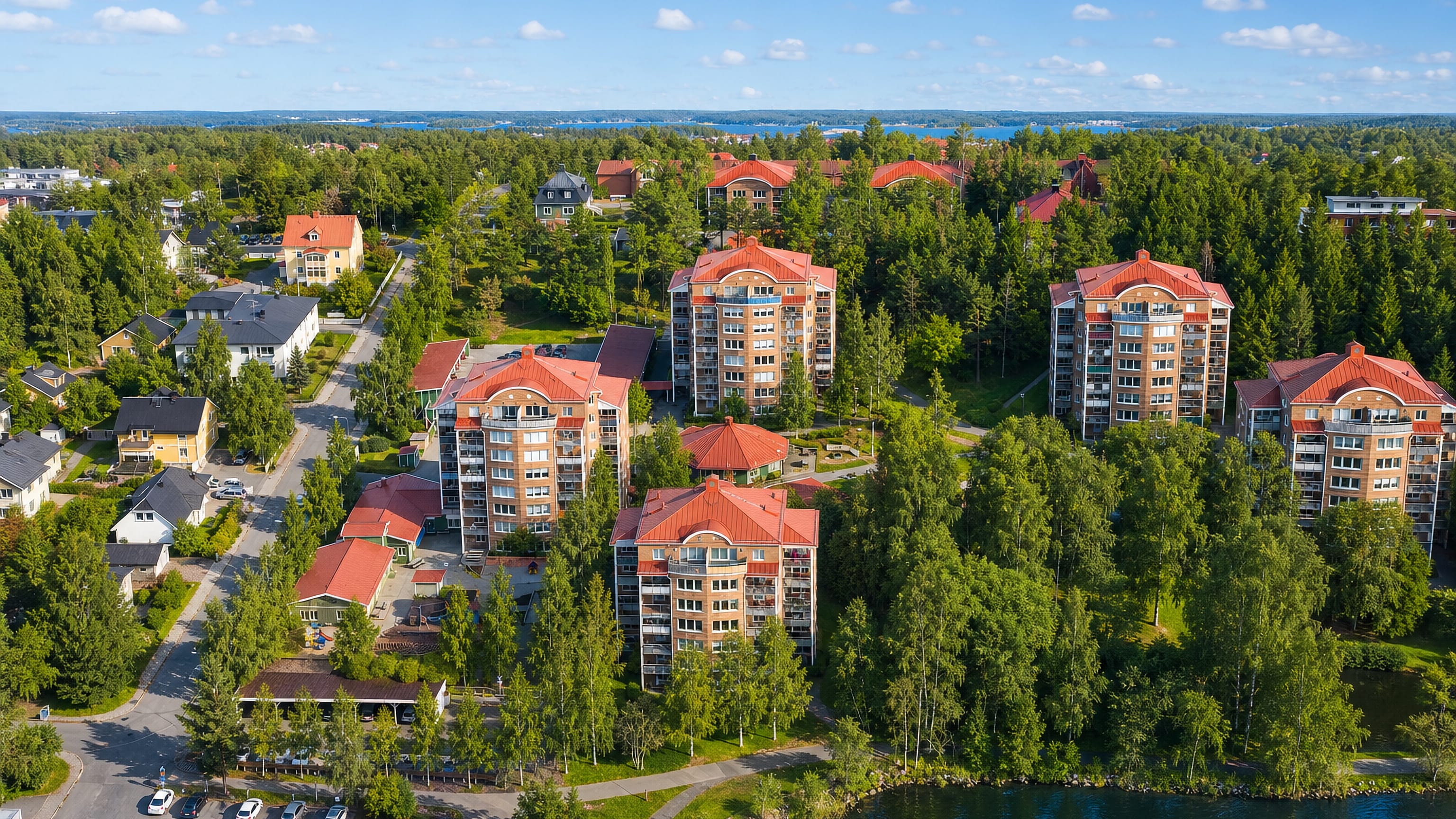 Aerial view of red-roofed apartment blocks among trees beside the water in Ostermalm, Lulea.