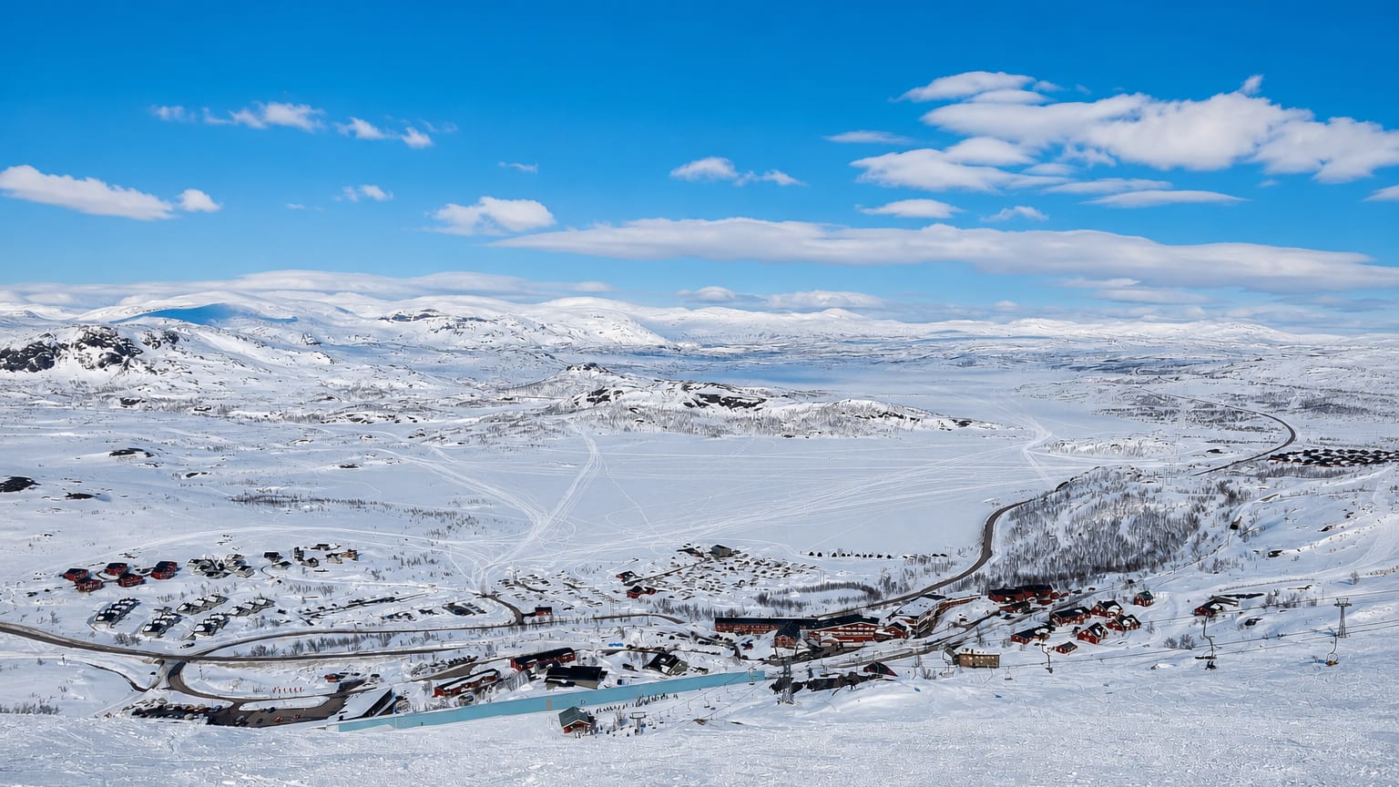 Snow-covered ski resort of Riksgraensen in Swedish Lapland with a cluster of lodges and lifts amid vast white fells.