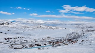 Snow-covered ski resort of Riksgraensen in Swedish Lapland with a cluster of lodges and lifts amid vast white fells.
