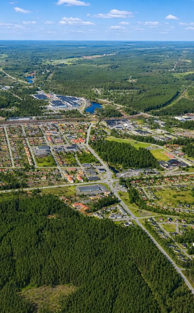 Aerial view of Laxå, a small Swedish town set among extensive pine forest under a blue summer sky.