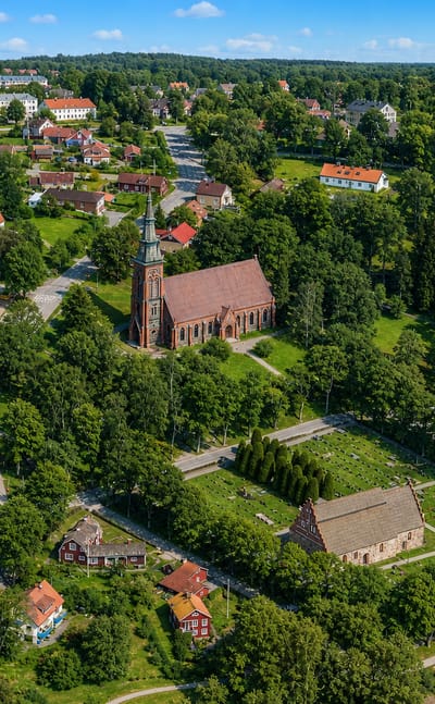 Aerial view of Åtvidaberg, Sweden, with a red-brick church, red-roofed houses and surrounding greenery on a sunny day