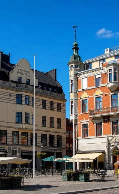 The historic Centralpalatset building on a paved square with cafe awnings and bicycles in central Linkoping