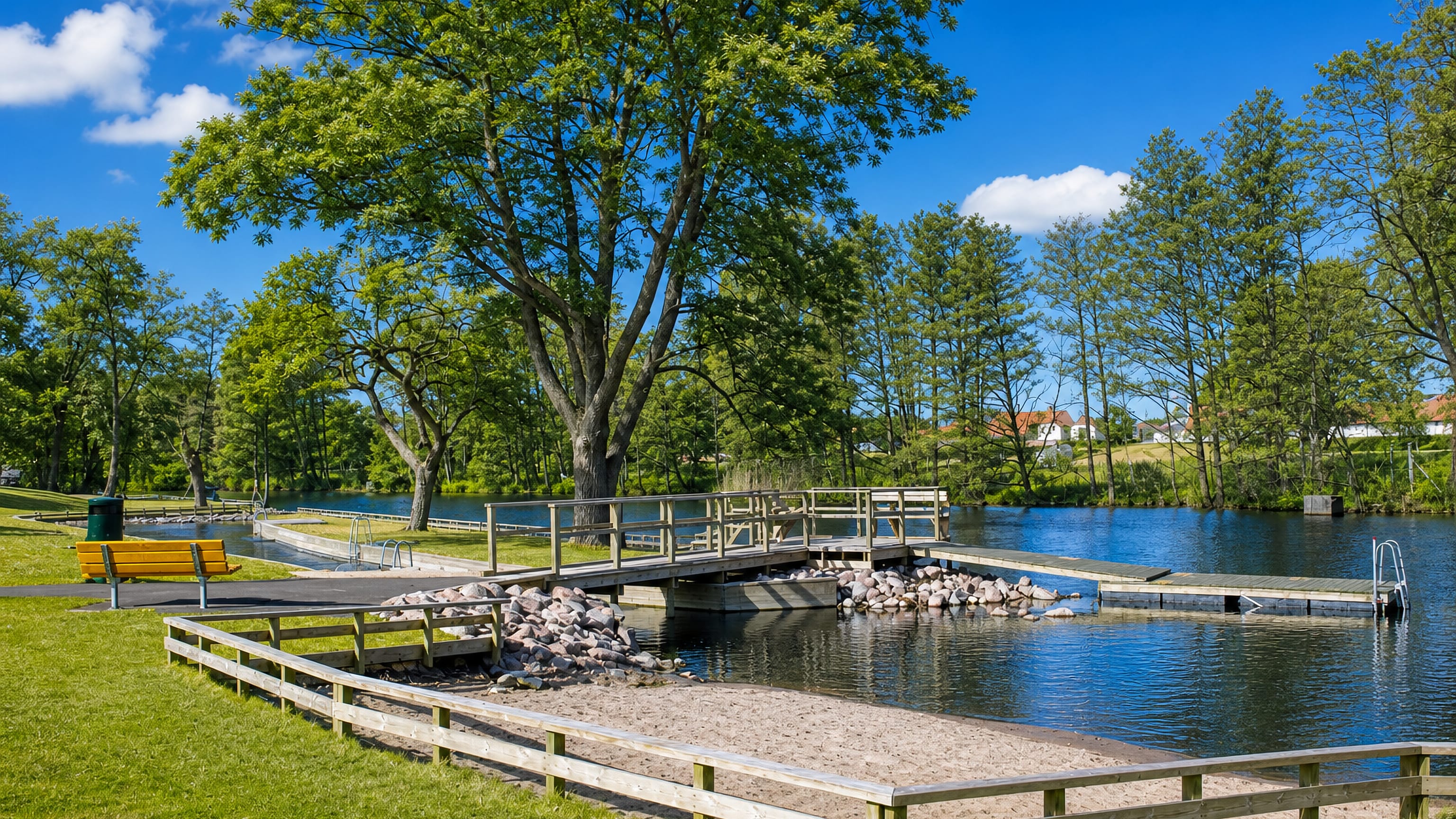 Wooden jetty, sandy bathing spot and lawns at a waterside park in Johannelund, Linköping.