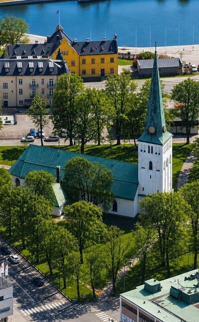 Aerial view of Motala, Sweden, with its green-spired church, tree-lined square and canal harbour behind.