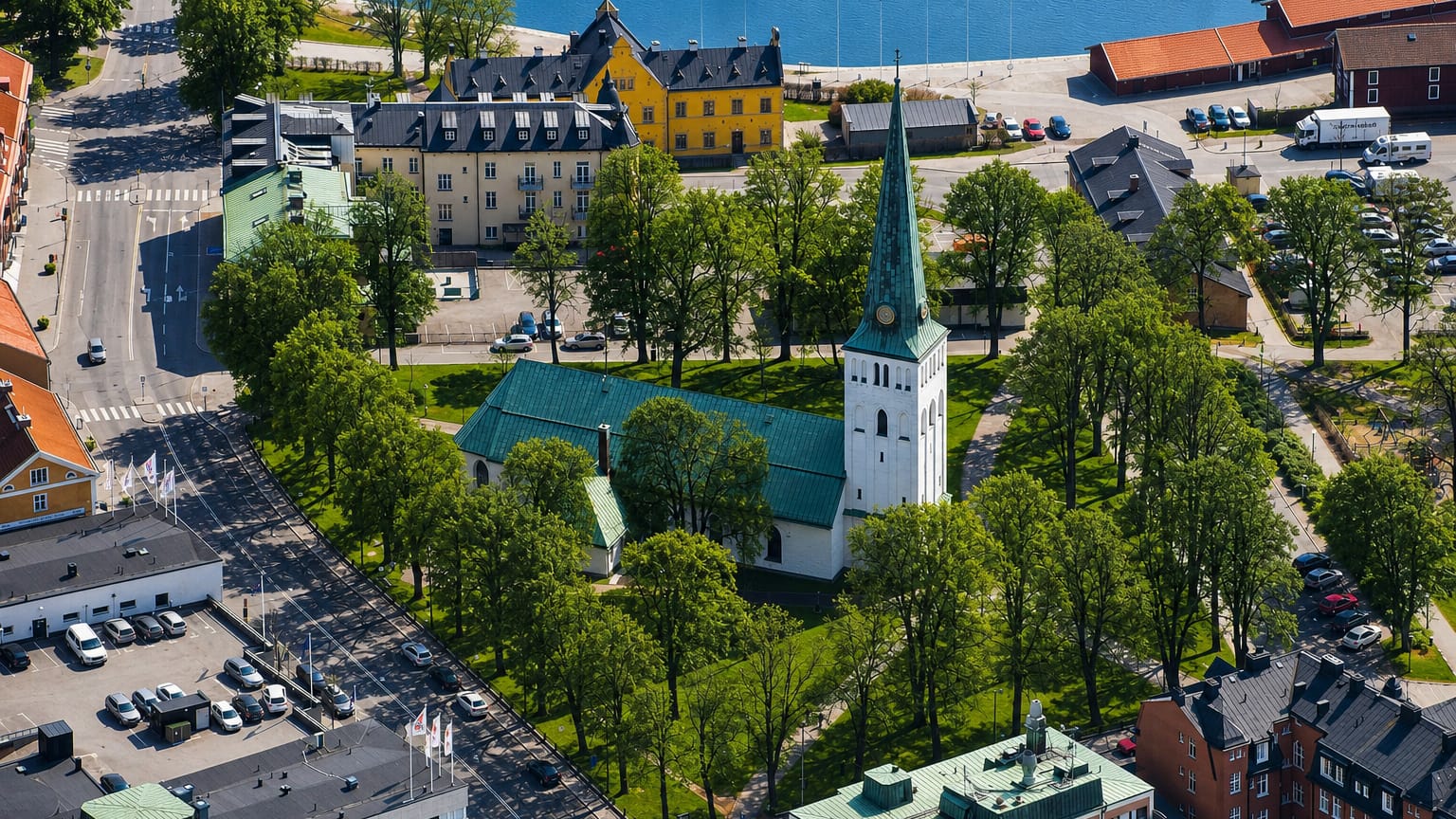 Aerial view of Motala, Sweden, with its green-spired church, tree-lined square and canal harbour behind.