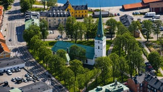 Aerial view of Motala, Sweden, with its green-spired church, tree-lined square and canal harbour behind.
