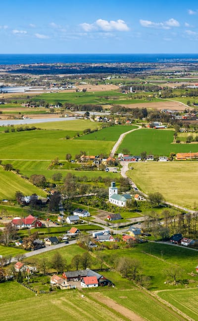 Aerial view over the green farmland and coastline of Bastad on Sweden's Bjare peninsula with the sea beyond