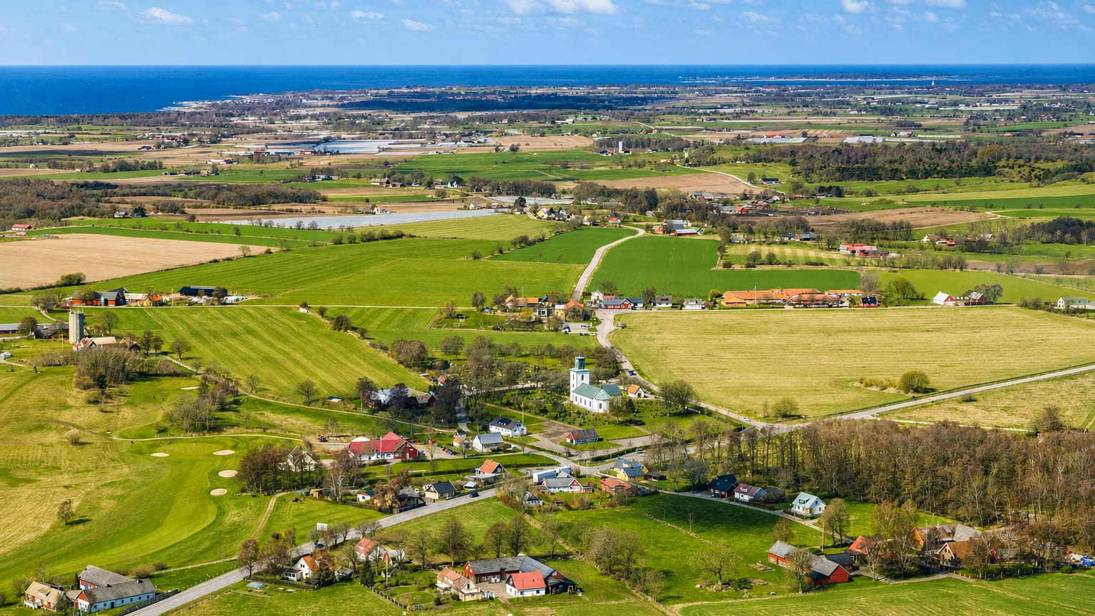 Aerial view over the green farmland and coastline of Bastad on Sweden's Bjare peninsula with the sea beyond