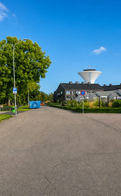 Residential street in Bjuv leading toward the town's distinctive white water tower under a blue sky