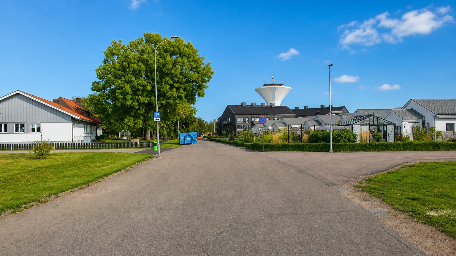 Residential street in Bjuv leading toward the town's distinctive white water tower under a blue sky