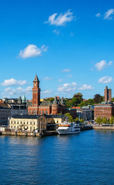 Helsingborg, Sweden, waterfront with the red-brick town hall clock tower and harbour boats under a blue sky
