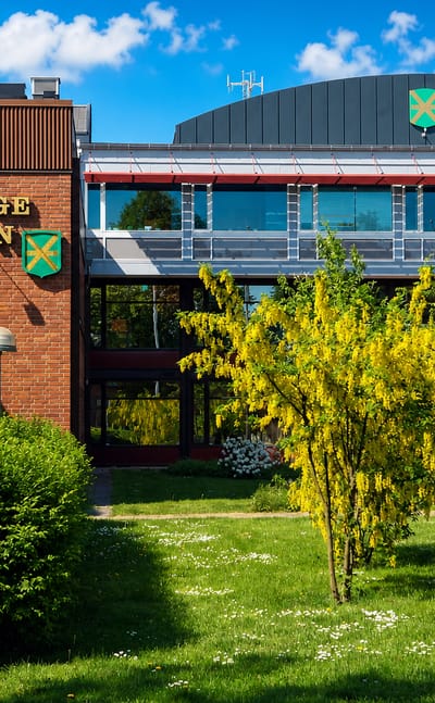 The red-brick Kavlinge Kommun municipal building with its crest and a landscaped garden in Kavlinge, Sweden.