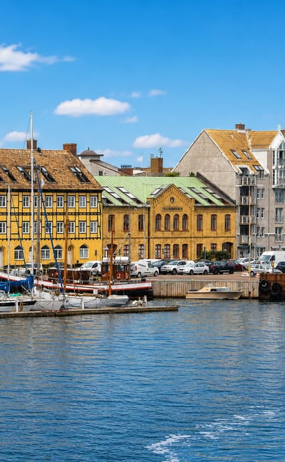 Harbour front of Landskrona, Sweden, with a yellow half-timbered warehouse, historic buildings and moored sailboats.