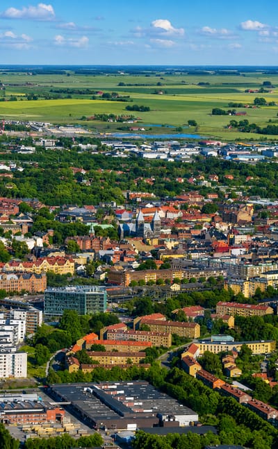 Aerial view over Lund, Sweden, with dense town blocks giving way to yellow rapeseed fields on the horizon