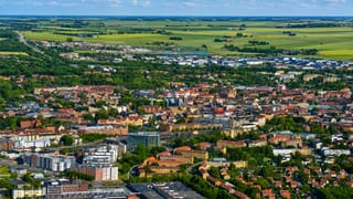 Aerial view over Lund, Sweden, with dense town blocks giving way to yellow rapeseed fields on the horizon