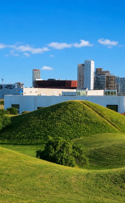Hyllie's water tower rising above the district's grassy green mounds and modern skyline in Malmö, Sweden.