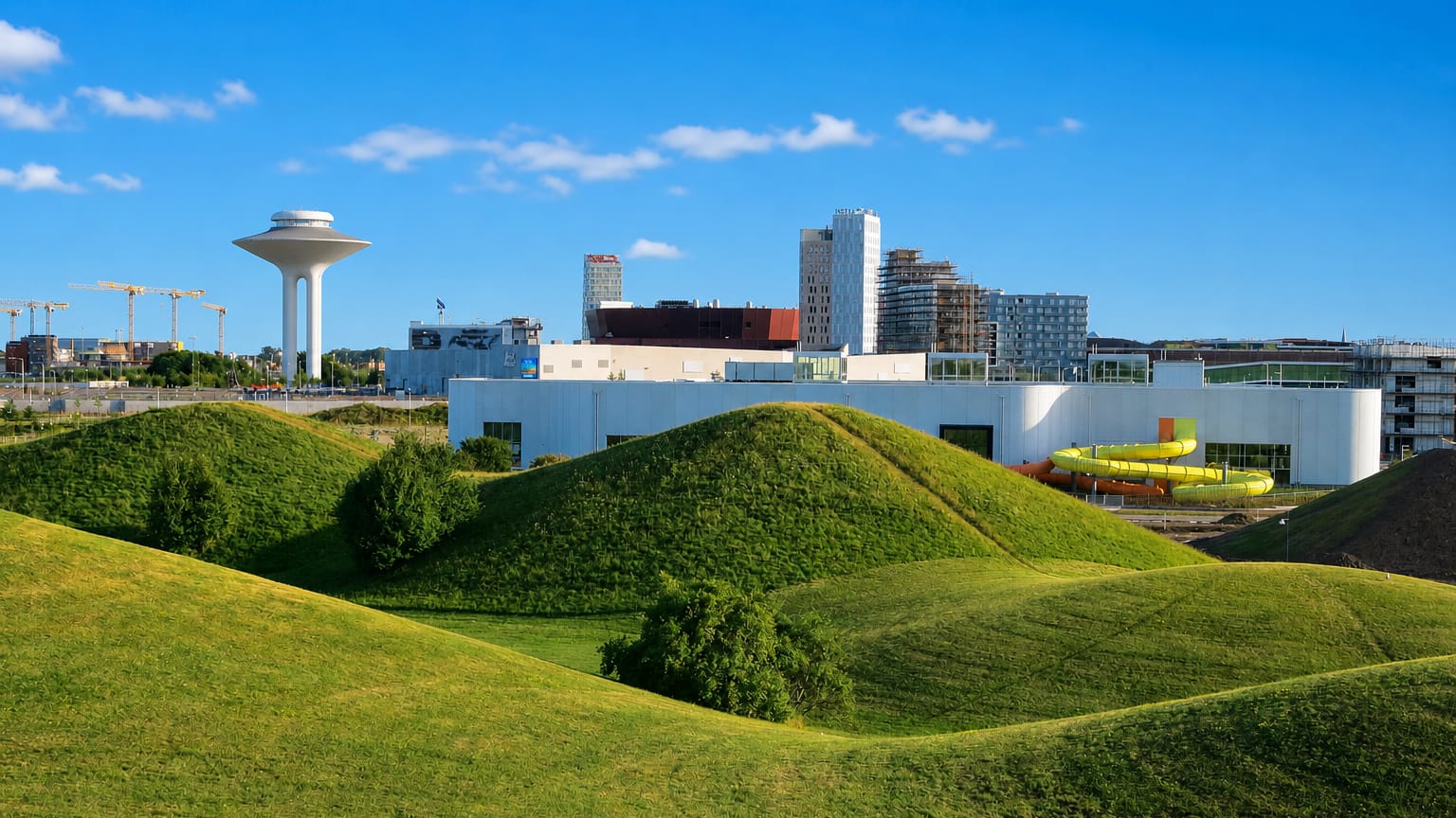 Hyllie's water tower rising above the district's grassy green mounds and modern skyline in Malmö, Sweden.