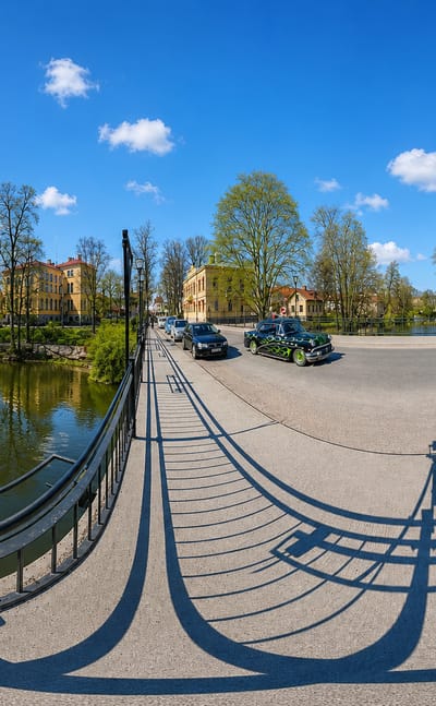 Fisheye river-bridge panorama in Nykoping, Sweden, with waterside old buildings and a red-brick turreted house.