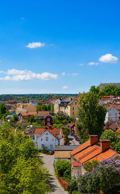 Rooftop view over Strängnäs, Sweden, its red-roofed old town rising to the large brick cathedral with Lake Mälaren beyond.