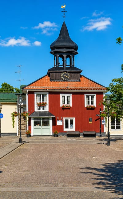 Trosa's red timber town hall with its black onion-domed bell tower rising over the cobbled main square, Sweden.