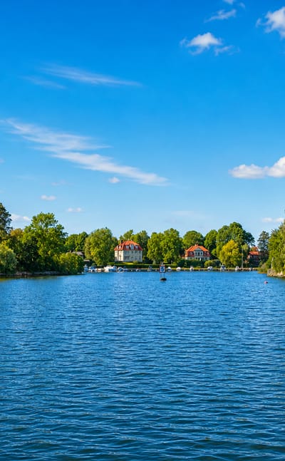 Waterfront villas and wooded shoreline of Djursholm across a calm blue bay near Stockholm