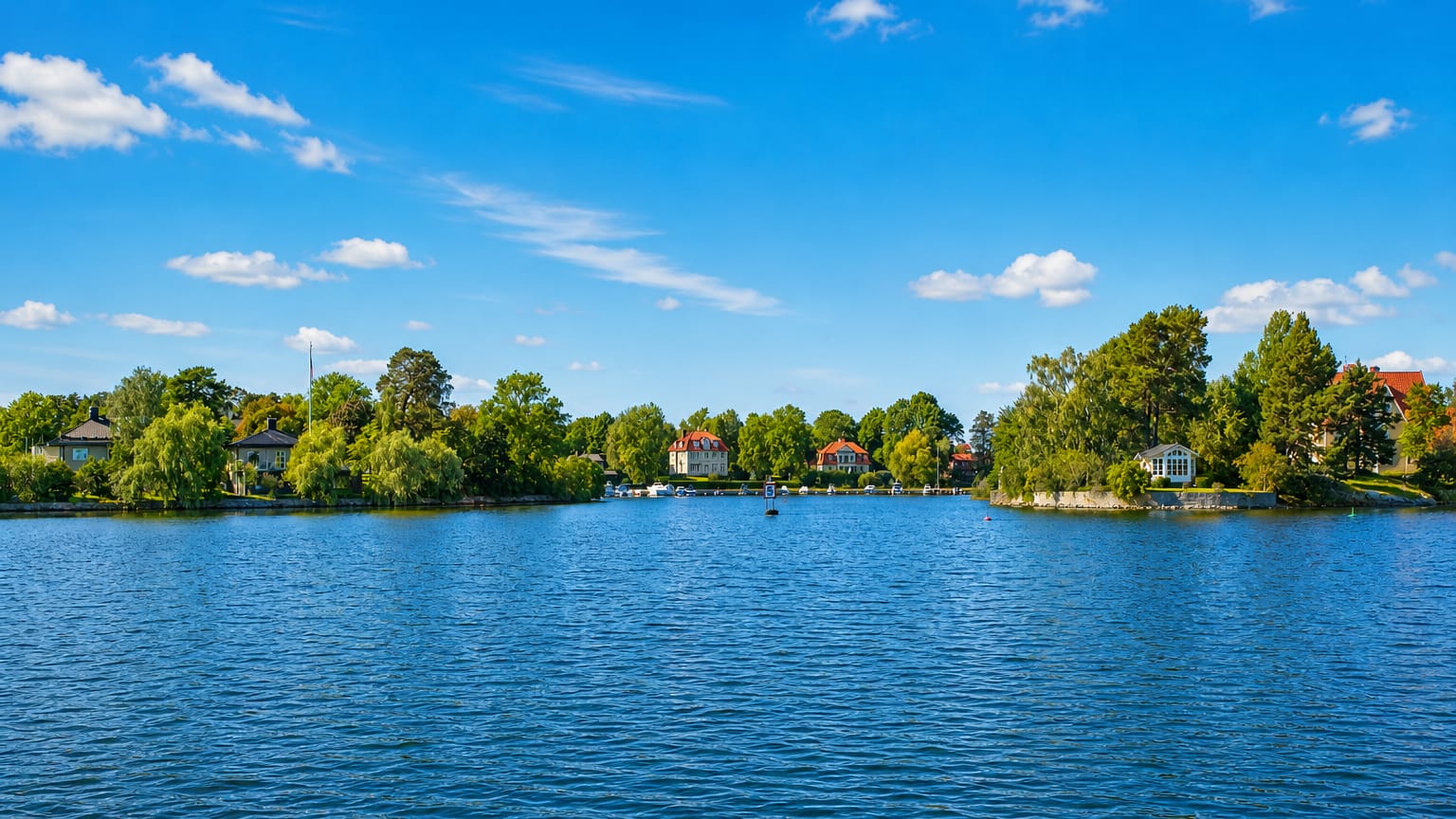 Waterfront villas and wooded shoreline of Djursholm across a calm blue bay near Stockholm