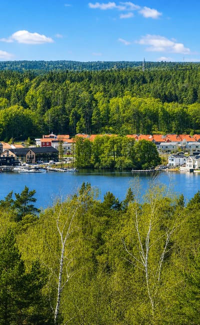 Lakeside village of Ekero, Sweden, with red-roofed houses along the shore framed by green trees