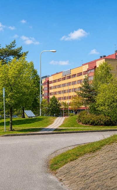 A curved yellow-and-red modern building among trees in the Stockholm suburb of Handen, Haninge.
