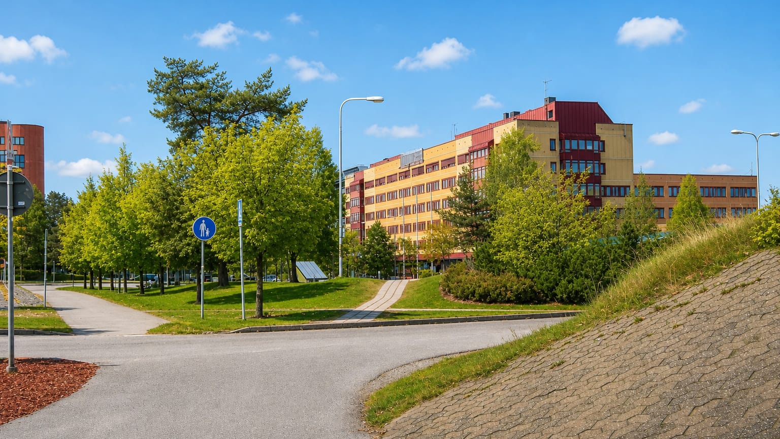 A curved yellow-and-red modern building among trees in the Stockholm suburb of Handen, Haninge.