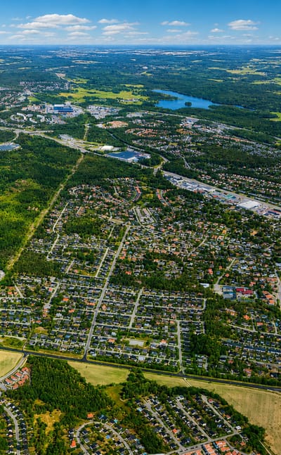 Aerial view of Jakobsberg's leafy suburbs, lakes and forests spreading toward the horizon near Stockholm.