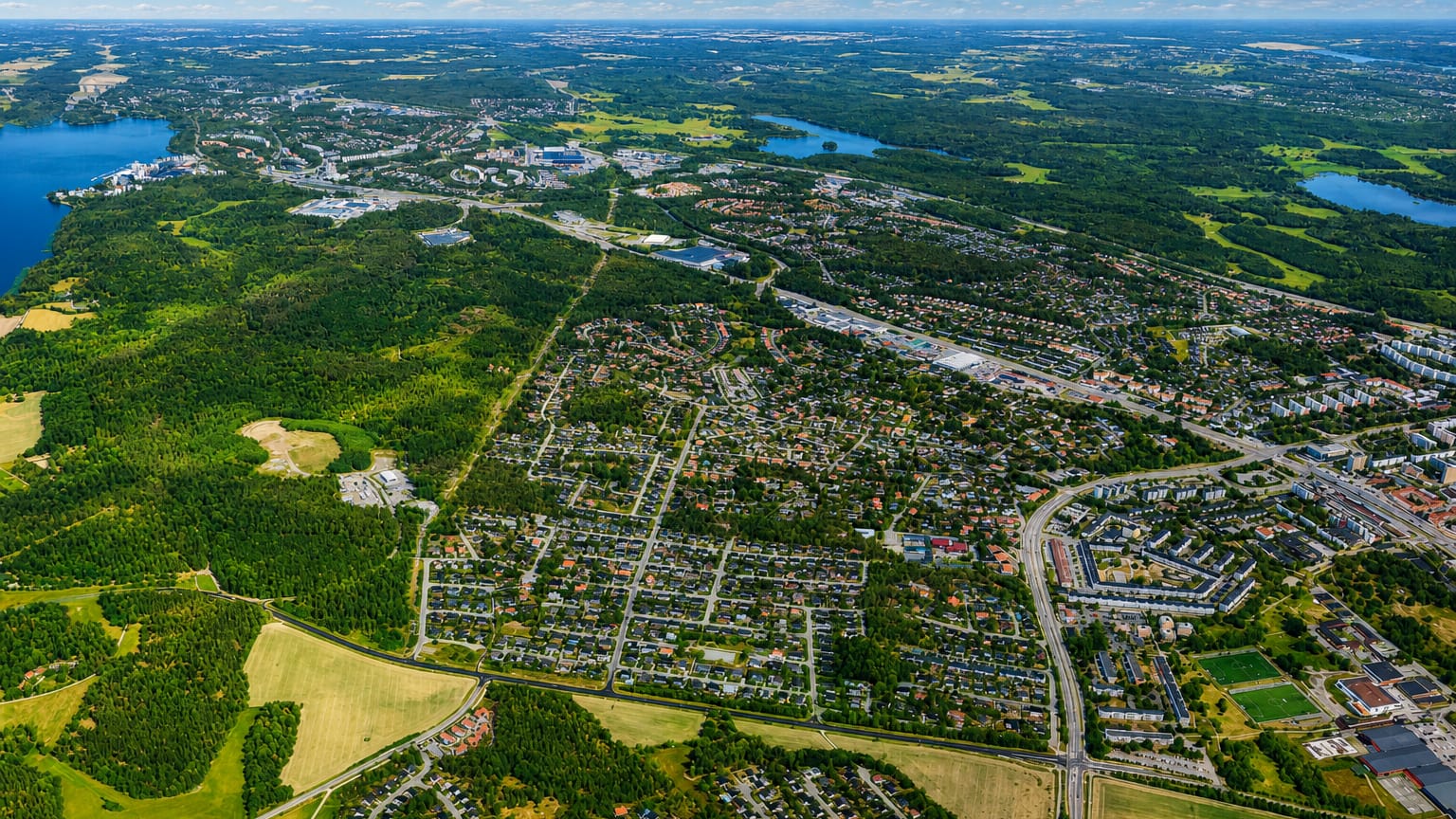 Aerial view of Jakobsberg's leafy suburbs, lakes and forests spreading toward the horizon near Stockholm.