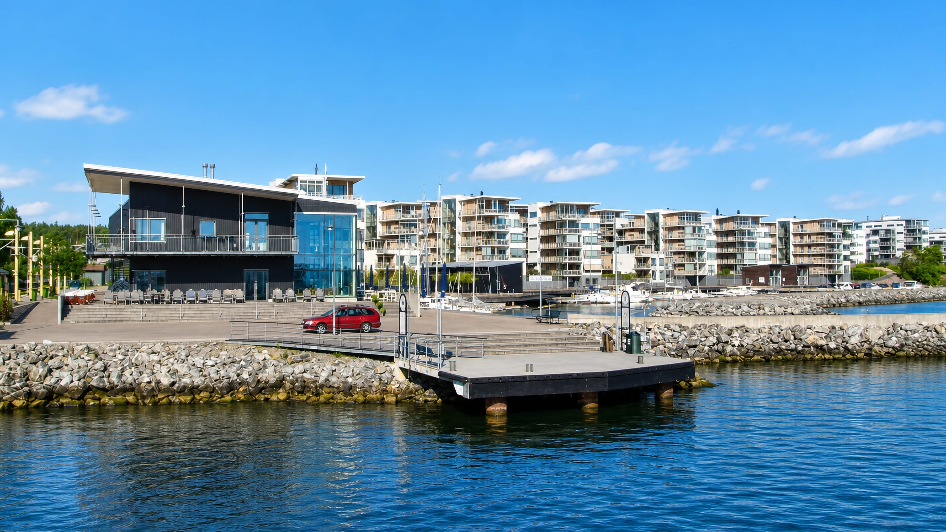 Waterfront apartments and a marina jetty at Gashaga on Lidingo, seen across the sunlit inlet.