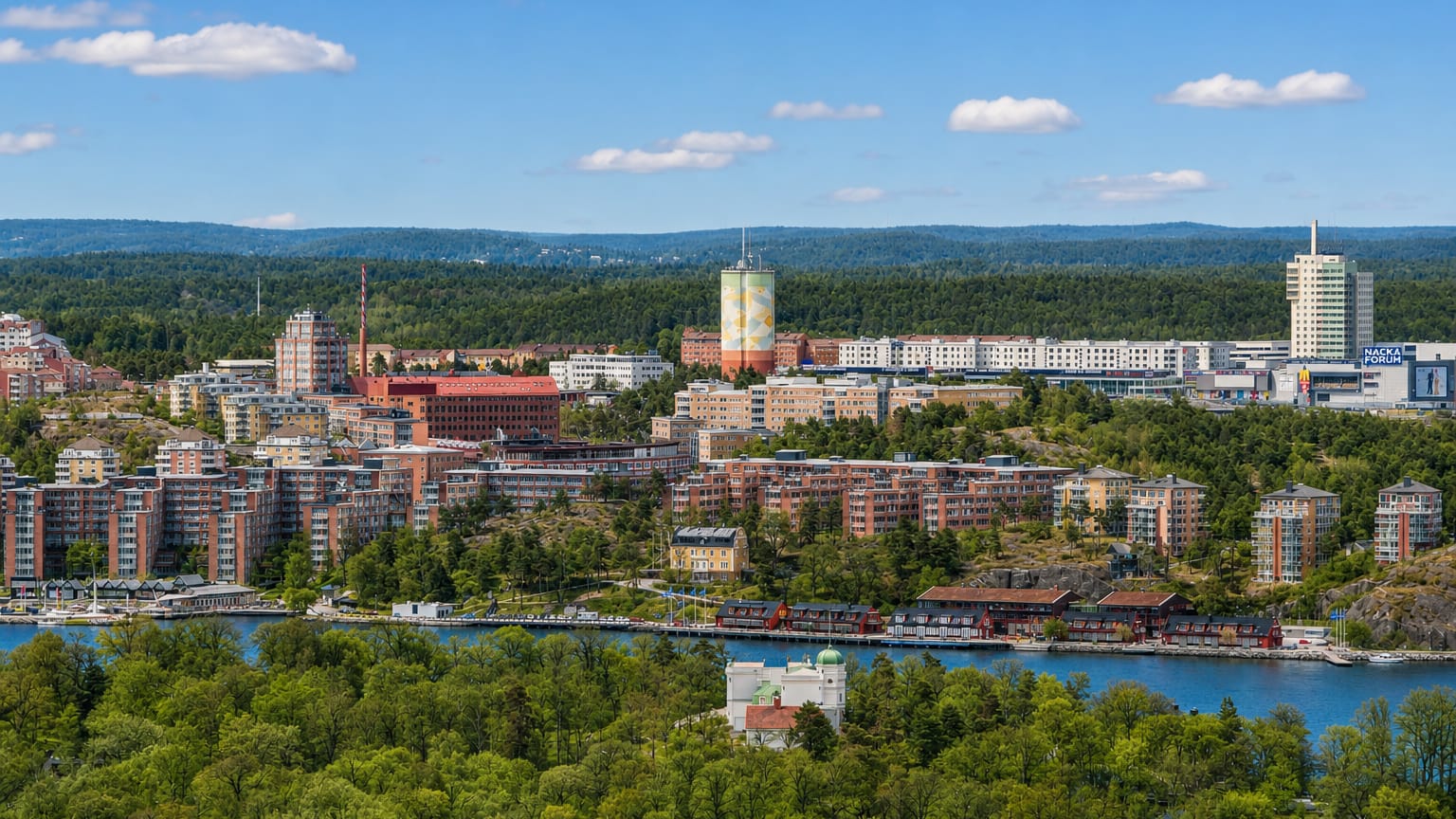 Nacka skyline in Sweden with apartment blocks, the painted water tower and Nacka Forum mall above the water.