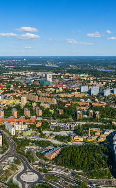 Aerial view over Solna, Sweden, showing apartment blocks, a roundabout and railway lines with Stockholm beyond