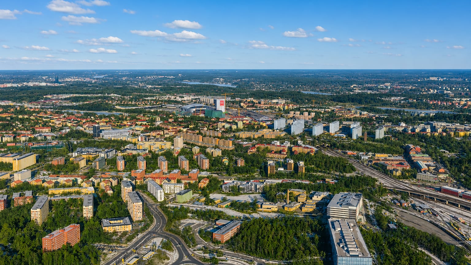 Aerial view over Solna, Sweden, showing apartment blocks, a roundabout and railway lines with Stockholm beyond