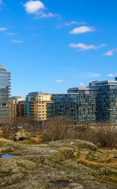 Modern glass office tower and apartment blocks above rocky bedrock terrain in Skytteholm, Solna, Sweden