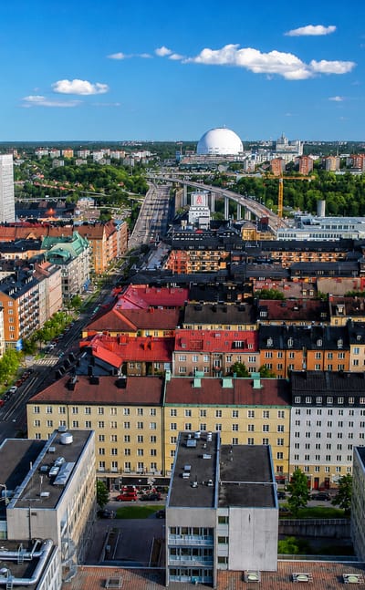 Aerial daytime view over Årsta's colourful apartment blocks in southern Stockholm with the Globen arena on the horizon