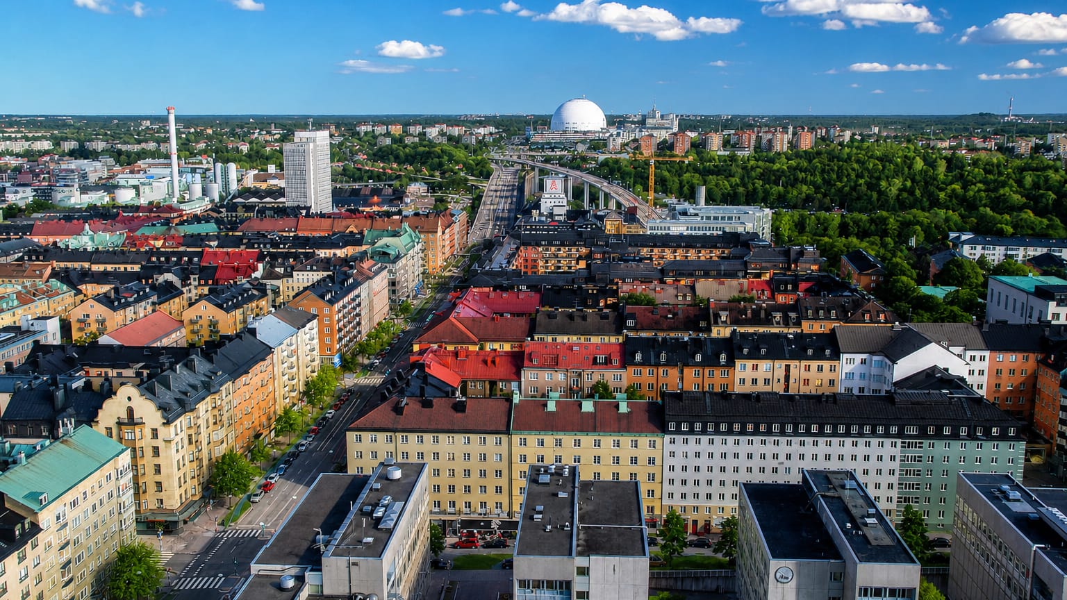 Aerial daytime view over Årsta's colourful apartment blocks in southern Stockholm with the Globen arena on the horizon