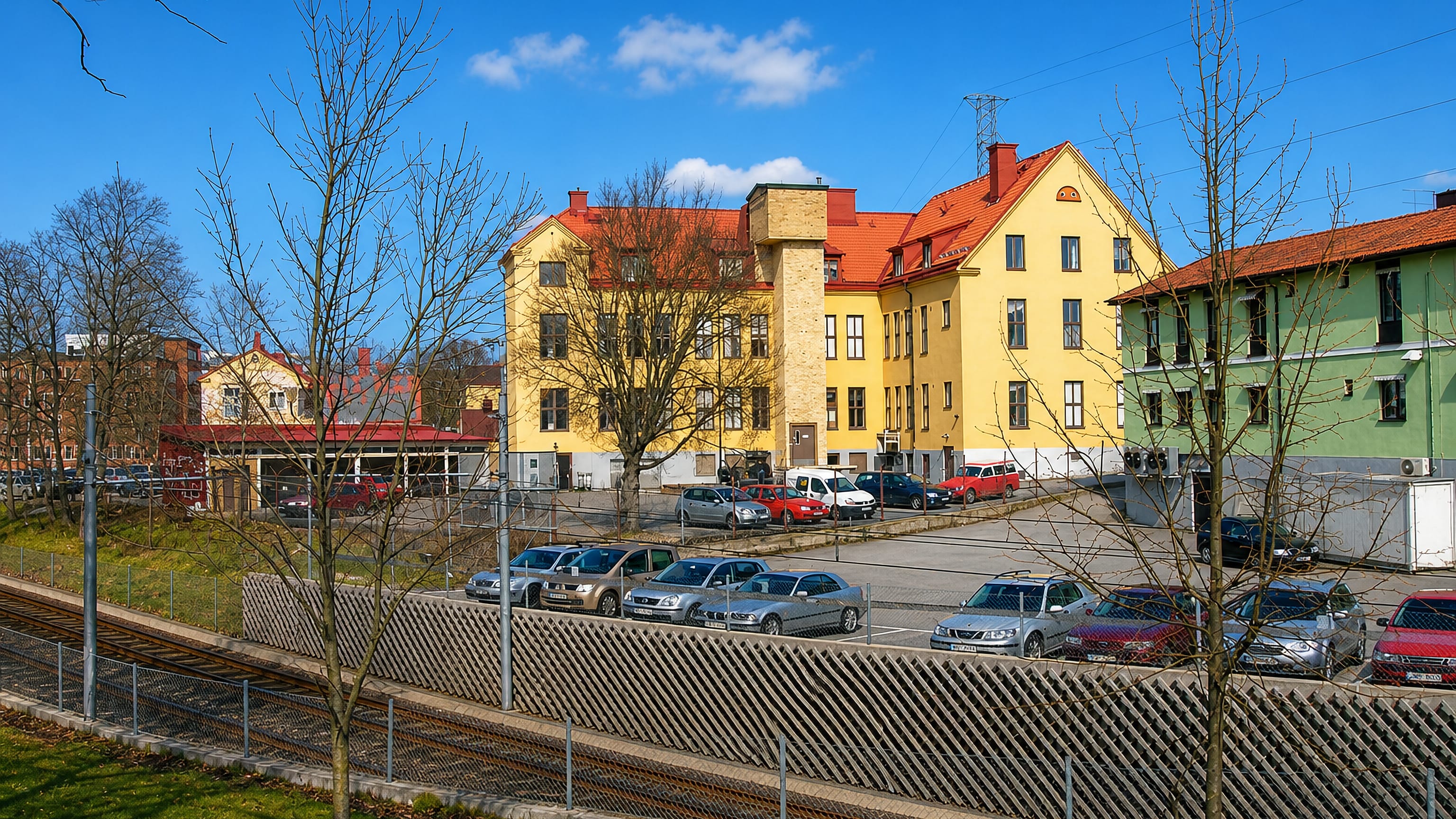 Yellow and green apartment blocks beside the railway and a car park in Enskede Gard, southern Stockholm