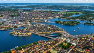 Aerial view of Gamla Stan's terracotta old-town islands, bridges and the blue waterways of central Stockholm.