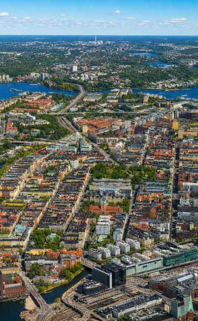 Aerial view of Kungsholmen, a dense city island in central Stockholm ringed by water and bridges under a clear sky.
