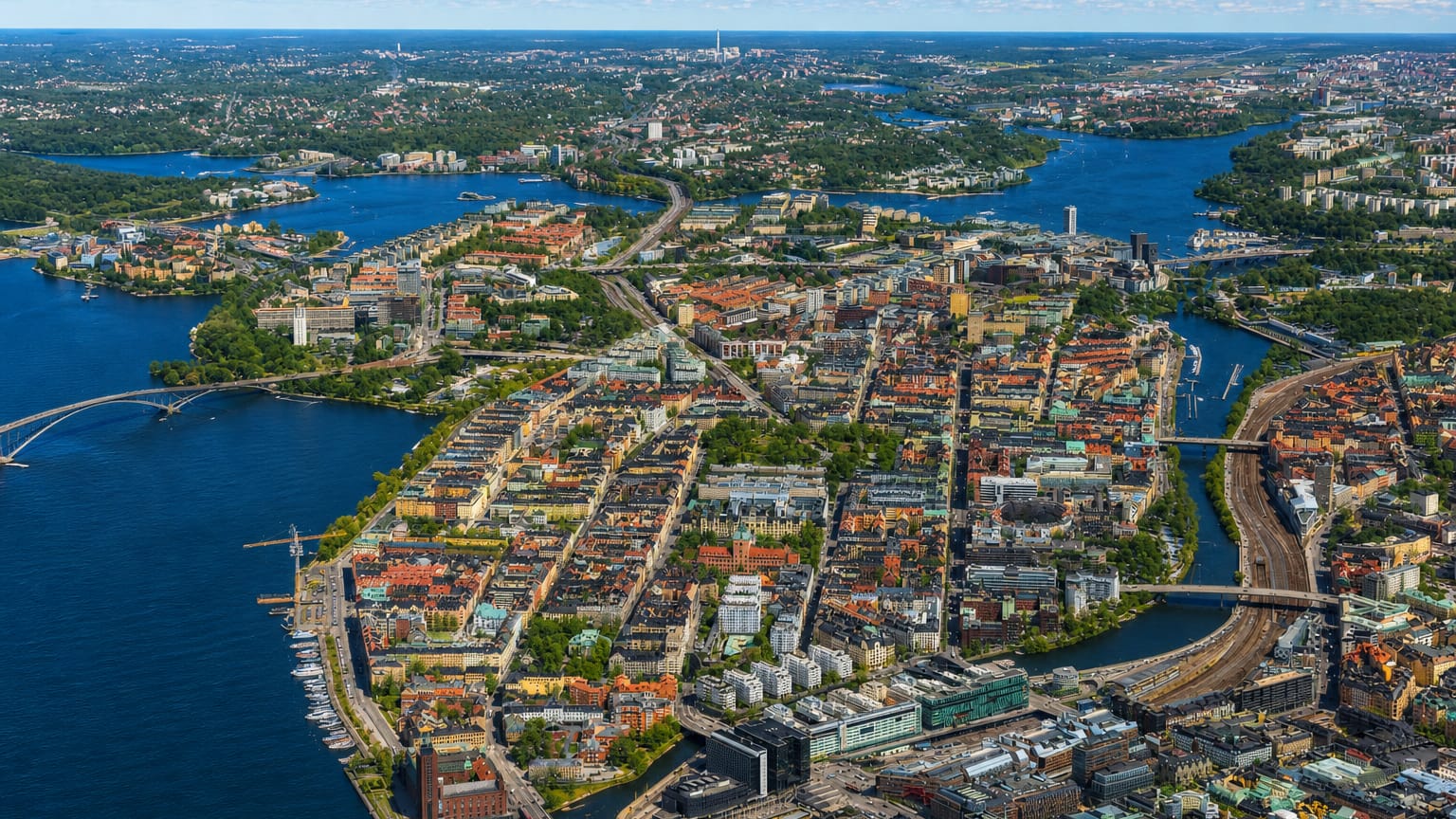 Aerial view of Kungsholmen, a dense city island in central Stockholm ringed by water and bridges under a clear sky.